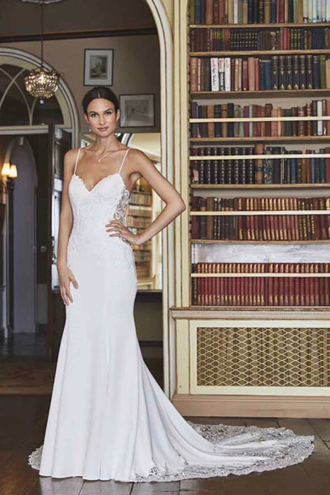 Woman modelling white lace wedding dress in front of bookshelf 1