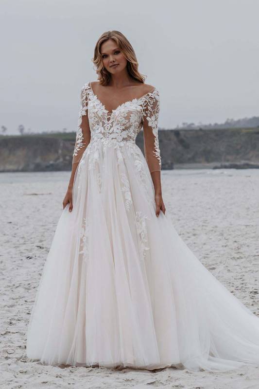 Ivory wedding dress with lace sleeves modelled on a beach